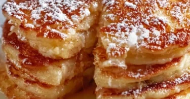 Delicious apple yogurt pancakes stacked on a plate with syrup drizzle.