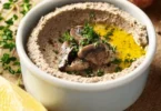 Homemade mushroom pâté served on a rustic bread with herbs and spices.