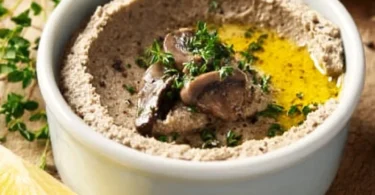 Homemade mushroom pâté served on a rustic bread with herbs and spices.