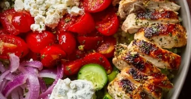 Delicious Greek Chicken Bowl topped with fresh vegetables and herbs