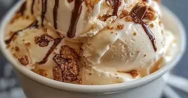 Scoop of malted milk toffee crunch ice cream in a cone with toffee bits