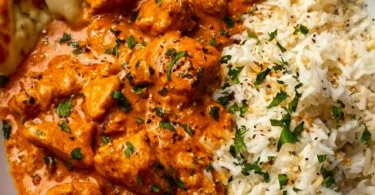 Delicious homemade butter chicken served with rice and garnished with cilantro.