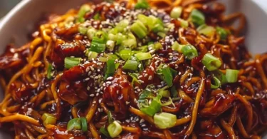 Delicious sticky garlic chicken noodles garnished with green onions.