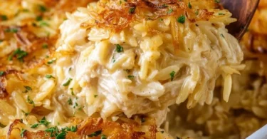 French Onion Chicken Orzo Casserole topped with melted cheese and herbs.