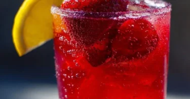 Hibiscus tea strawberry-lemonade refresher served in a glass with ice and garnished.